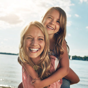 mother giving daughter piggy back ride