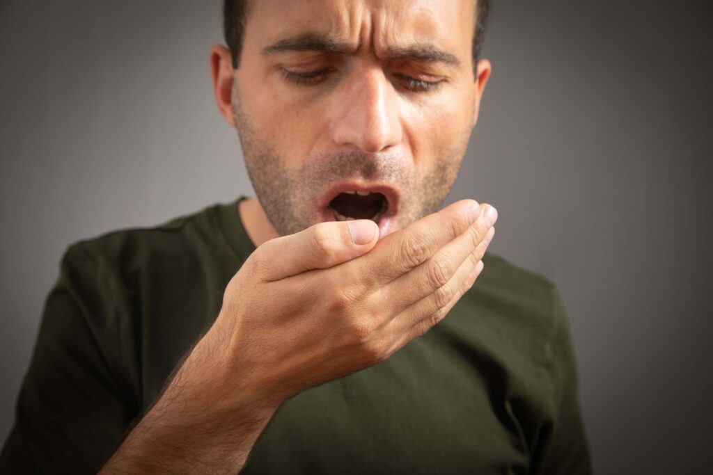 Person checking for bad breath by covering the mouth, concern for oral hygiene in Creve Coeur, MO