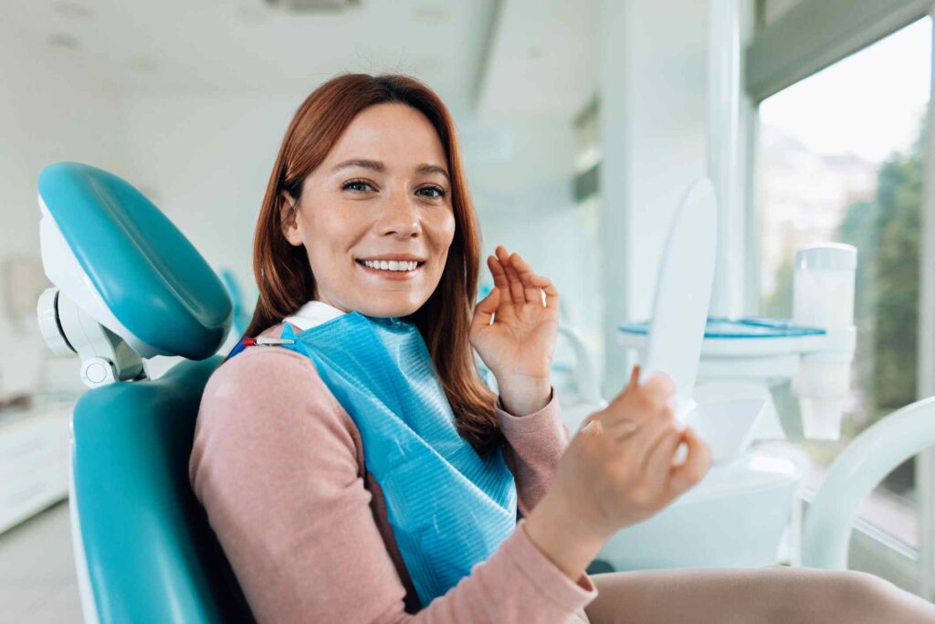 Patient examining teeth in a mirror after a dental implant at the clinic in Creve Coeur, MO