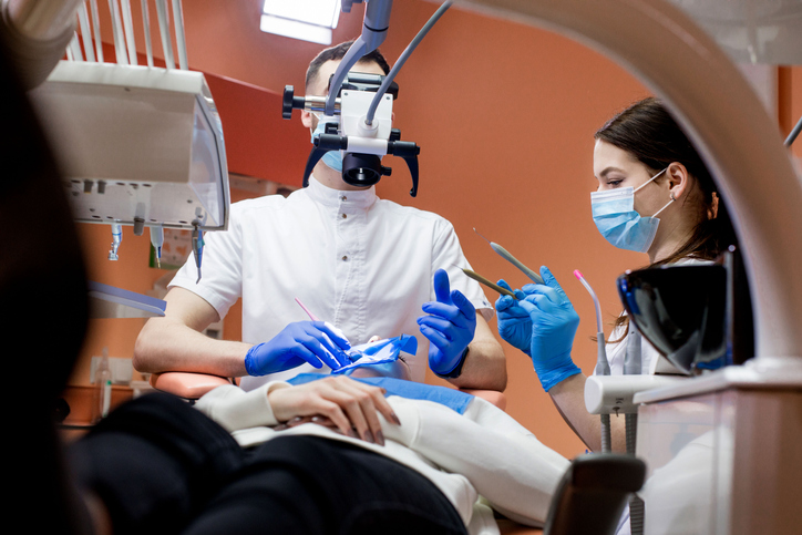A dentist treats a woman's teeth using a cofferdam. Dental equipment.